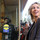 Elizabeth Holmes stands with the door open to her as cameras surrounding her snap pictures.